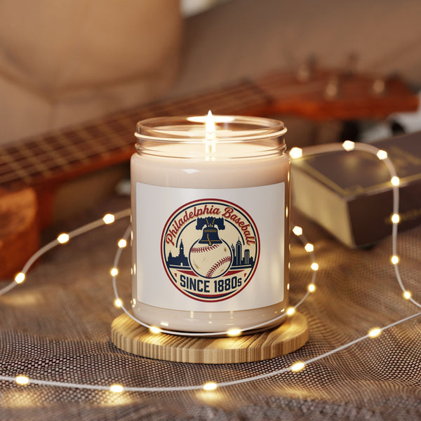 Candle in a jar with a baseball-themed label on a wooden coaster, surrounded by string lights and a guitar in the background.